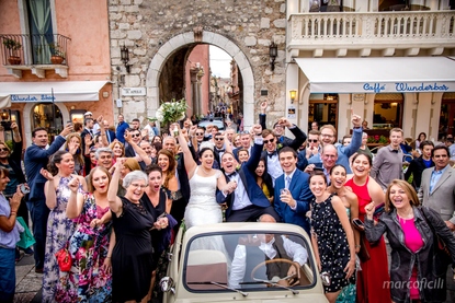 Bride and Groom have fun with their guests in a vintage Fiat 500 cabriolet in Piazza IX Aprile Taormina