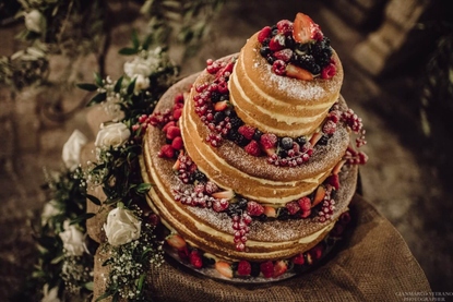 Naked wedding cake with luscious red fruits and pretty white roses in Taormina