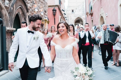 Bride and Groom hand in hand strolling along the Corso Umberto in Taormina with local folk style musicians