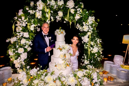 Luxury wedding cake with cascade of kumquats and white peonies under a beautiful floral archway on the beach in Taormina